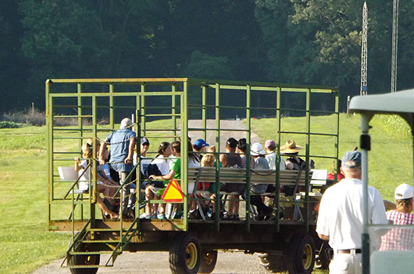 People on a wagon pulled by a tractor.