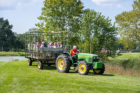 A tractor pulling a hay wagon with a group of people on it.