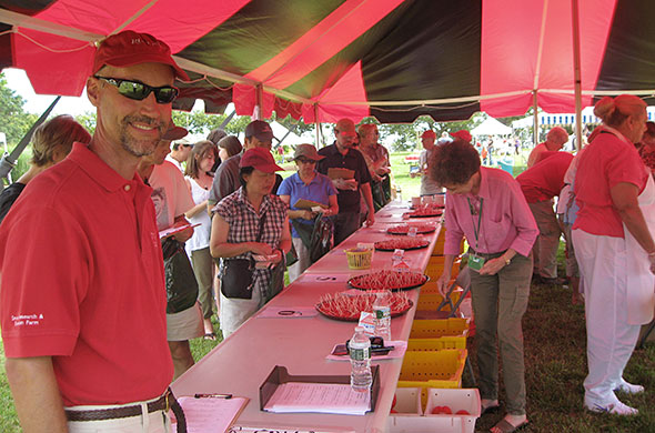 People tasting tomatoes under a tent.