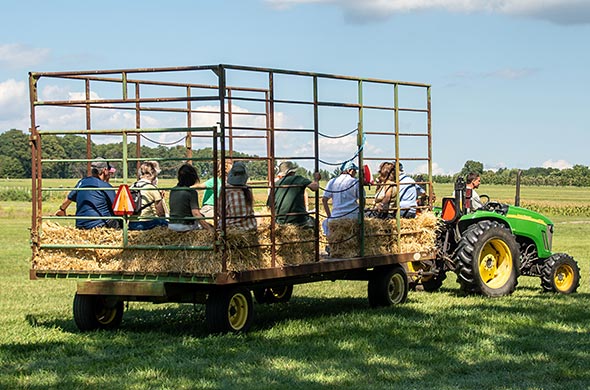 A tractor pulling a hay wagon with a group of people on it.