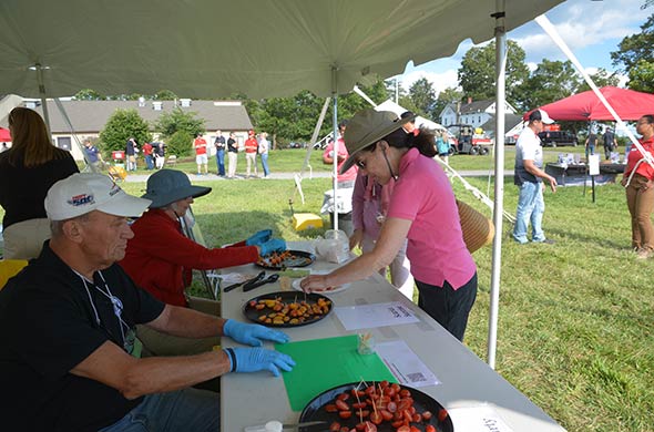 People offering varieties of tomatoes for tasting.