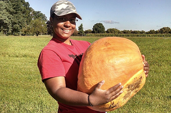 Student intern with a large pumpkin.